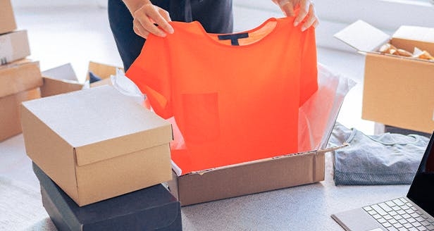 Una persona doblando una camiseta naranja